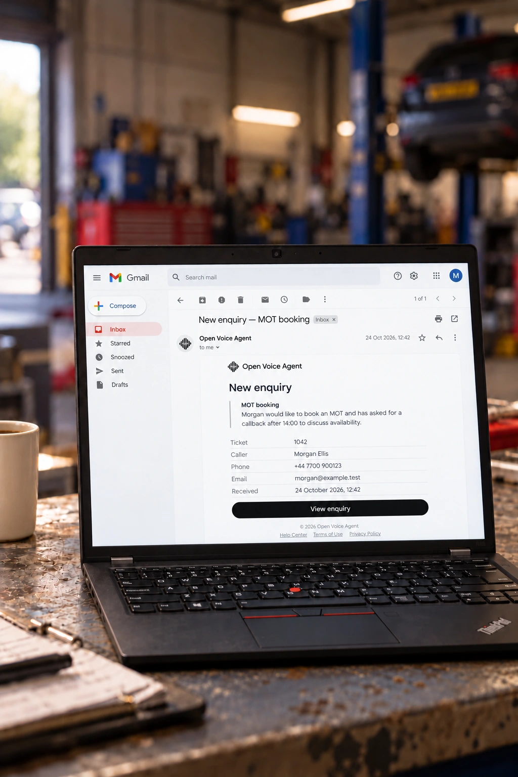 A ThinkPad showing a branded MOT enquiry email open in Gmail in a UK mechanic’s garage